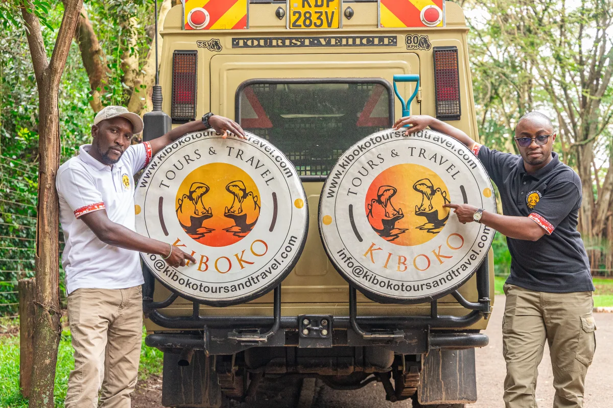 Two Kiboko driver guides beside a safari Land Cruiser